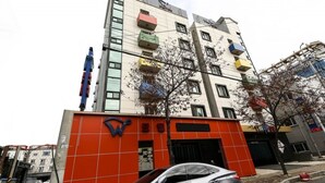 A multi-story building with a modern design, featuring balconies and a prominent entrance with a red and white color scheme. - W Motel (Tongyeong)