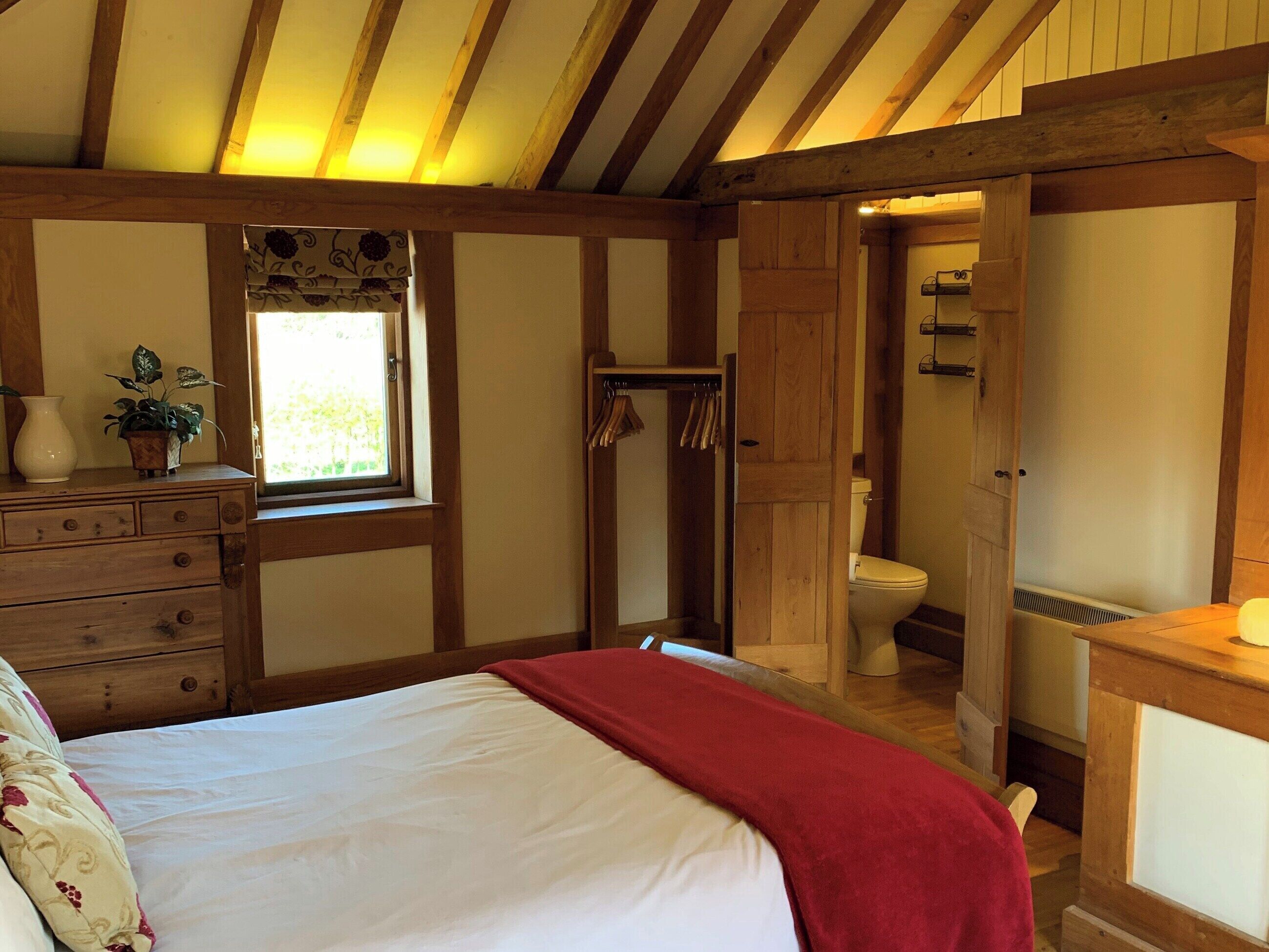 A bedroom with a bed, dresser, and a window with a view.