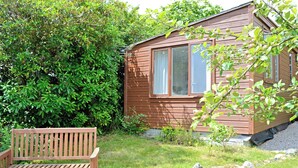 A wooden bench, a stone pathway, and a small house with windows and a door. - 1 bedroom accommodation in Nancledra, near Penzance (Nancledra, near Penzance)