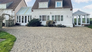 A house with a gravel driveway, a conservatory, and a glass-roofed room. - 1 bedroom accommodation in Stalham (Stalham)