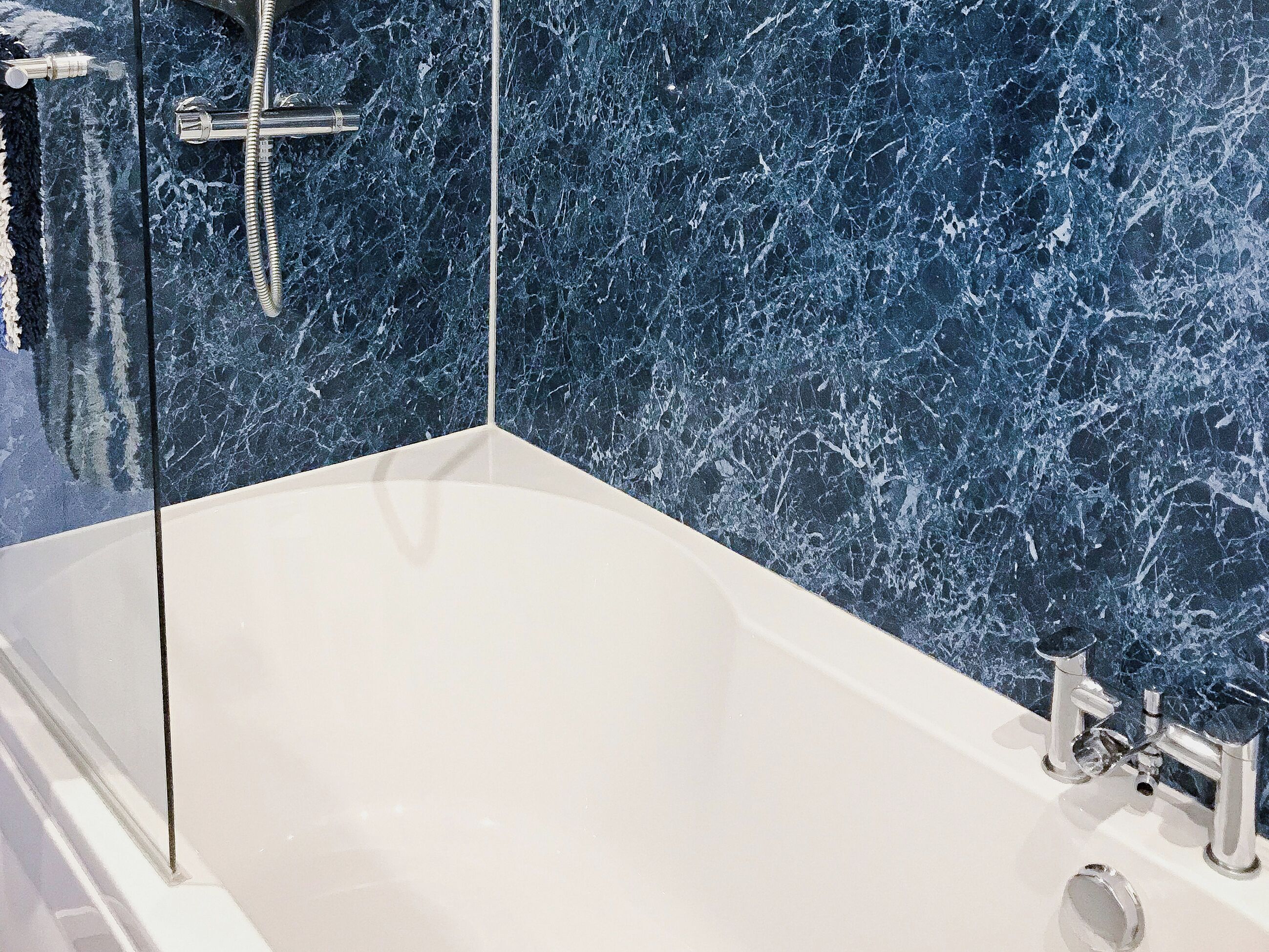 Une baignoire à l’intérieur blanc, avec une pomme de douche et un robinet.