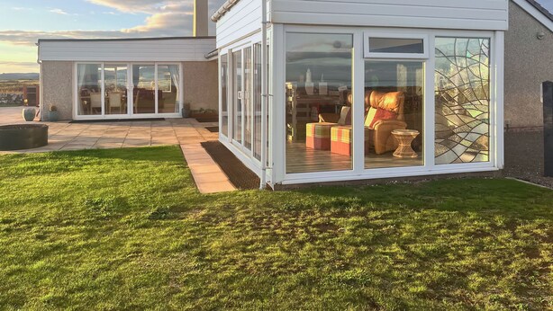 Uma casa moderna com um pátio, portas de correr e vista para a paisagem.