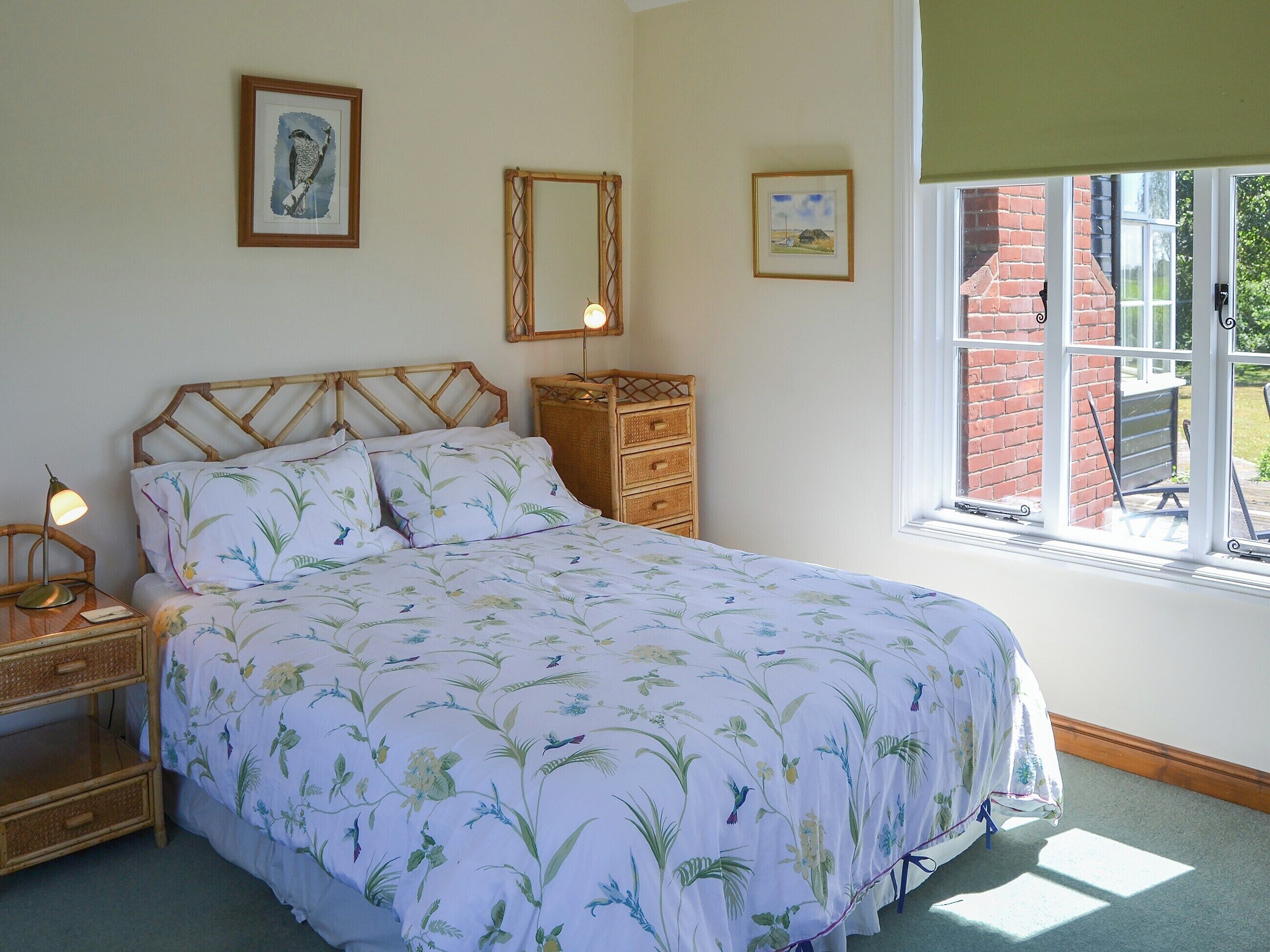 A bedroom with a bed, bedside tables, a dresser, and a window with a view of a brick building.