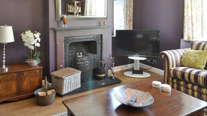 Ein Wohnzimmer mit Kamin, Fernseher, Sofa und Dekoration.