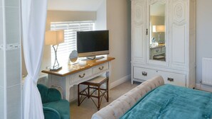 Ein Schlafzimmer mit einem Bett, einem Fernseher auf einem Holztisch, einem Kleiderschrank und einem Sessel.