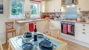 A modern kitchen with a dining area, equipped with a stove, oven, and various utensils. - Barn Owl Cottage - 27941 (Stirling)
