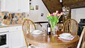 Ein Esstisch mit Stühlen, eine Blumenvase, Weingläser und eine Weinflasche.