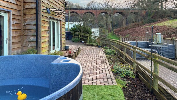 Une maison en bois avec un jacuzzi, un chemin en briques et une clôture en bois.