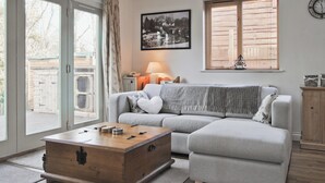 Un salon avec un canapé gris, une table basse en bois, une lampe et un tableau au mur.