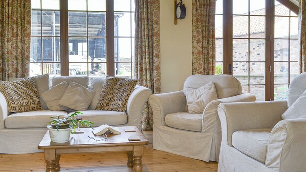 A room with a sofa, armchairs, a wooden coffee table, and large windows with curtains. - 3 bedroom accommodation in near Easingwold (near Easingwold)