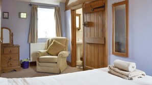 A bedroom with a bed, a chair, a dresser, a wooden wardrobe, a radiator, and a window with curtains. - 3 bedroom accommodation in near Easingwold (near Easingwold)