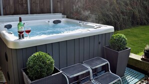 A hot tub with a bottle and glass, surrounded by a wooden fence and potted plants. - 3 bedroom accommodation in near Easingwold (near Easingwold)