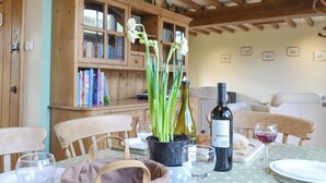 A dining area with a wooden table, chairs, a bookshelf, and a wine bottle. - 3 bedroom accommodation in near Easingwold (near Easingwold)