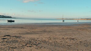 Ein Strand mit Booten, ruhigem Wasser und blauem Himmel.