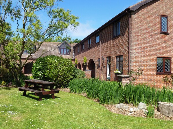 A brick building with a garden, a picnic table, and a clear blue sky.