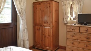Ein Schlafzimmer mit einem Holzschrank, einem Fernseher auf einer Kommode und einem Bett mit floralem Bettbezug.