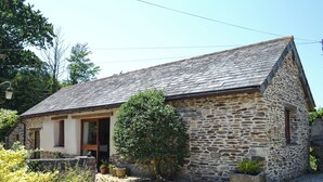 A stone building with a sloped roof, a wooden door, and a small window. - 1 bedroom accommodation in Mevagissey (Mevagissey)