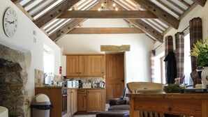 A rustic kitchen with wooden beams, a stone wall, and a clock. - 1 bedroom accommodation in Mevagissey (Mevagissey)
