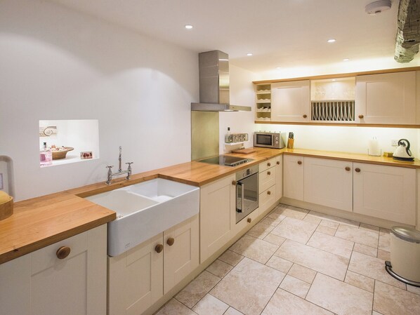 A modern kitchen with wooden countertops, a double sink, a microwave, and a built-in oven.