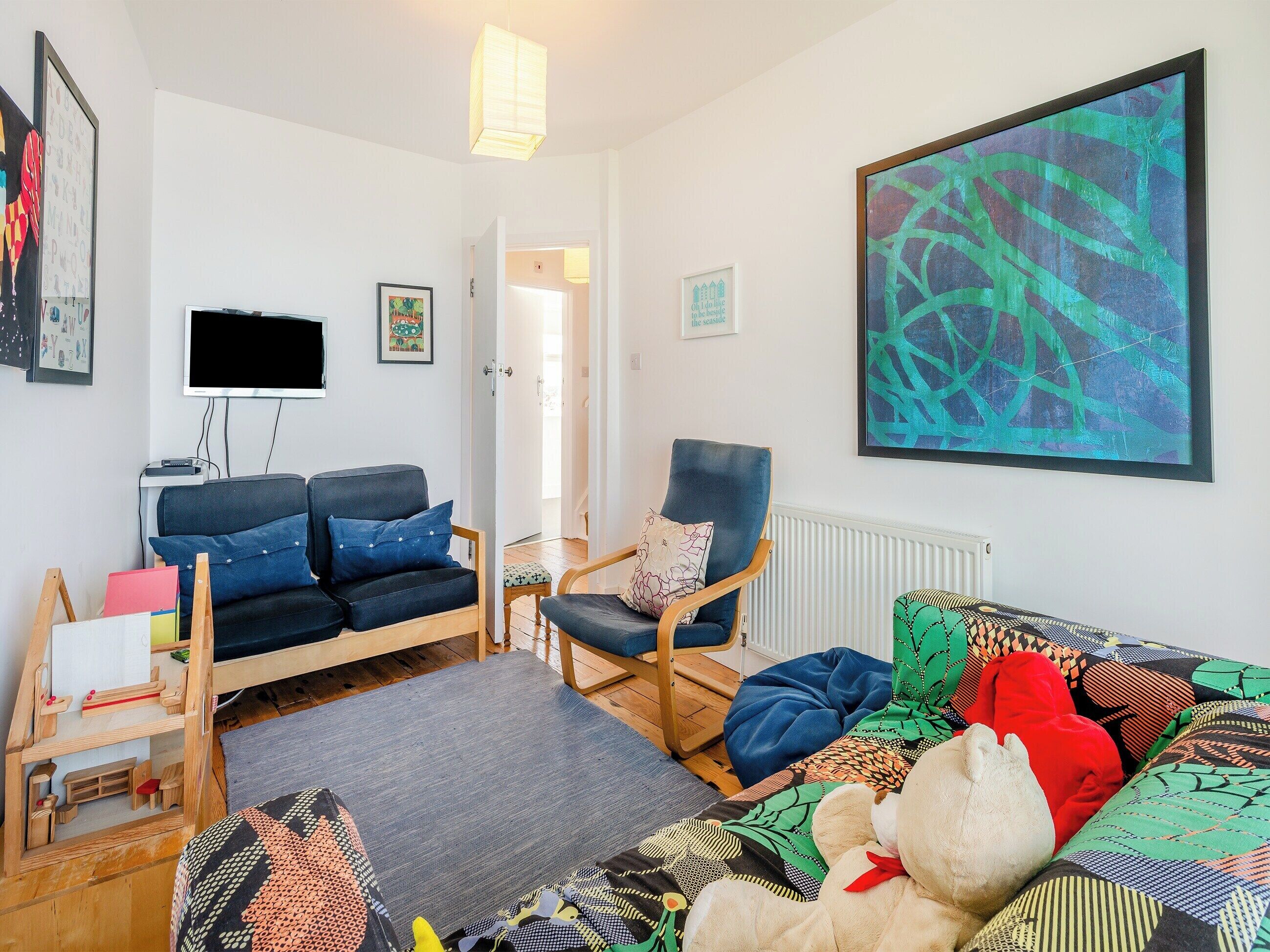 A living room with a sofa, armchair, and a large abstract painting.