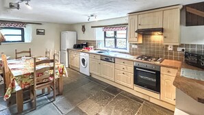 A kitchen with a dining table, chairs, a washing machine, a stove, and tiled flooring. - Cider House is a paradise for families, friends and couples. (Hawkchurch, near Lyme Regis)