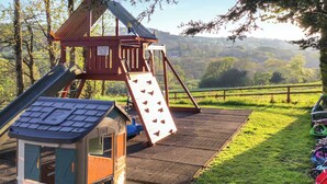 A playground with a slide, a climbing structure, and a small playhouse. - Cider House is a paradise for families, friends and couples. (Hawkchurch, near Lyme Regis)