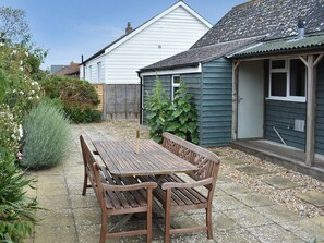 Ein Holztisch mit Bänken in einem Garten, im Hintergrund ein Haus.