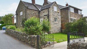 Une maison en pierre avec une allée pavée et un portail en métal.