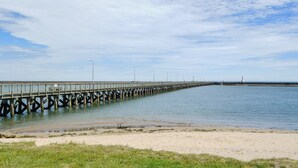 A pier extending into calm waters with a lighthouse in the distance. - 4 bedroom accommodation in Warkworth (Warkworth)