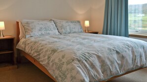 A bedroom with a bed, two bedside tables, and a window with curtains. - 2 bedroom accommodation in Fasach, near Dunvegan (Fasach, near Dunvegan)