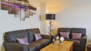 Un salon avec un canapé en cuir marron foncé, deux fauteuils assortis, une table basse en bois et un lampadaire.