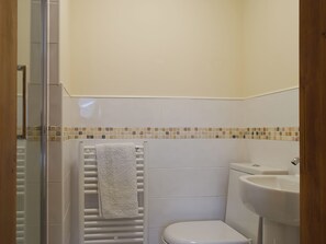 A bathroom with a shower, toilet, and sink. - An attractive luxurious ground floor apartment in the centre of Keswick. (Keswick)