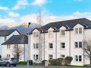 A multi-story building with a flat roof, multiple windows, and a sign indicating parking for residents only. - An attractive luxurious ground floor apartment in the centre of Keswick. (Keswick)