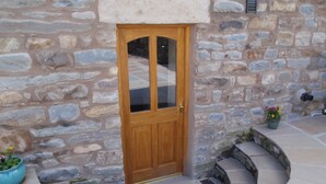 A stone building with a wooden door, stone steps, and potted plants. - Gateside Farmhouse Sedbergh (Sedbergh)