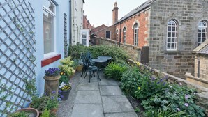 A narrow alley with a small outdoor seating area, potted plants, and a stone building. - 3 bedroom accommodation in Staithes, near Whitby (Staithes, near Whitby)