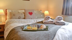 A neatly made bed with a tray of breakfast items, including two glasses of orange juice and a pastry, in a well-lit room with a framed picture on the wall. - 1 bedroom accommodation in Salem, near Llandeilo (Salem, near Llandeilo)