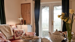 A cozy living room with a sofa, a coffee table, and a view of the outdoors through a glass door. - 1 bedroom accommodation in Salem, near Llandeilo (Salem, near Llandeilo)