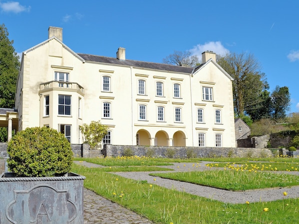 A large, cream-colored building with multiple windows and a stone base.