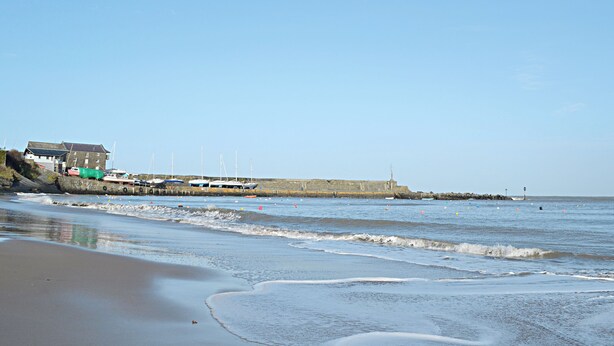 A coastal scene with a building near the shore, a pier with boats, and a lighthouse in the distance. - 1 bedroom accommodation in Salem, near Llandeilo (Salem, near Llandeilo)