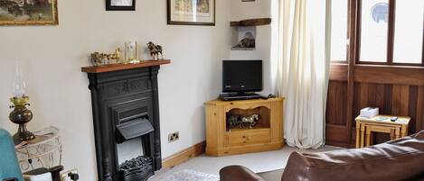 A living room with a fireplace, a television, a sofa, and a small wooden table.