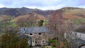 A stone house with a sloped roof, surrounded by trees and hills. - 4 bedroom accommodation in Guardhouse (Guardhouse)