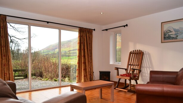 A living room with a sofa, a wooden table, a chair, and a fireplace. - 4 bedroom accommodation in Guardhouse (Guardhouse)