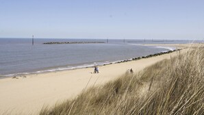 Ein Strand mit blauem Himmel, ruhiger See und sandigem Ufer.