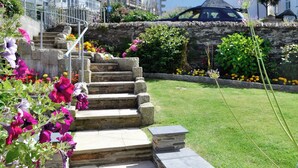 A stone staircase leading up to a building, surrounded by a well-maintained garden with various flowers and plants. - Atlantic House - 27665 (Port Isaac)