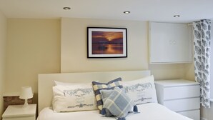 A neatly arranged bedroom with a bed, pillows, a bedside table, a lamp, a framed picture on the wall, and a wardrobe. - 4 bedroom accommodation in Keswick (Keswick)