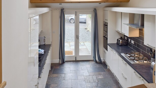 A modern kitchen with a skylight, stone flooring, and a view of the street through a glass door. - 4 bedroom accommodation in Keswick (Keswick)