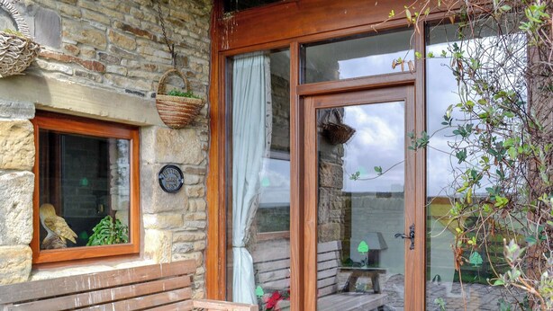 A wooden bench outside a stone building with a window and a door.