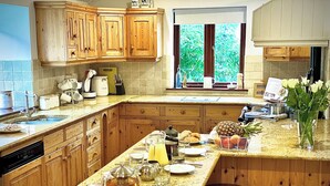 Une cuisine avec des meubles en bois, un plan de travail en granit et un coin repas équipé de tabourets.