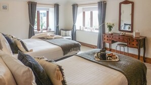 Une chambre d’hôtel avec deux lits, une commode en bois, un miroir et une fenêtre avec des rideaux.
