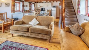Un salon chaleureux avec un plafond en bois, un canapé, une table basse et un escalier menant à un niveau supérieur.